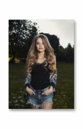 Glamorous young woman with long wavy hair in stylish outfit