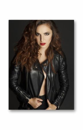 Beautiful young woman posing in black leather jacket over grey background. Fashion concept.