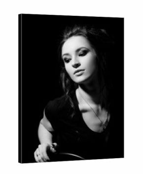 Girl in black T-shirt and with make-up sits on chair and looks down on black background close-up