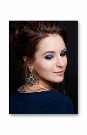 A brunette girl with makeup and a wedding hairstyle looks down close-up on a black background
