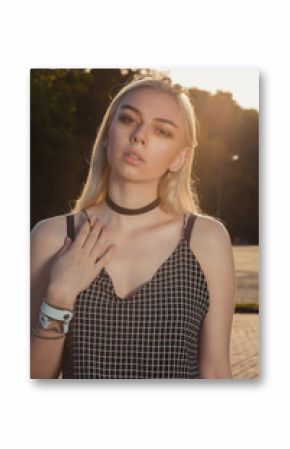 Closeup portrait of seductive tanned blonde girl in black romper posing at the city in rays of sun