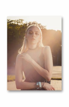 Closeup portrait of sexy tanned blonde girl in black romper posing at the city in sun glare