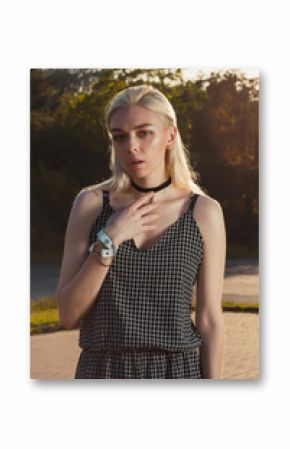 Pretty tanned blonde woman in black romper posing at the city in rays of sun