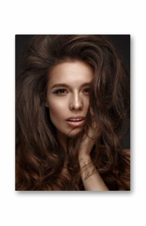 Beautiful brunette model with volume curls, classic makeup and sexy lips. The beauty of the face. Portrait shot in the studio.