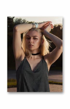 Glamor blonde woman wearing chocker, bracelet and romper posing in the city at the evening