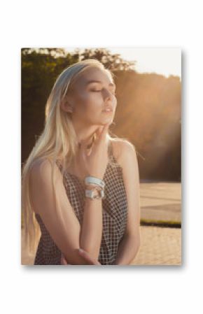 Stylish blonde model in black romper posing in the city in sunny day