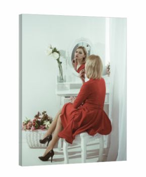 Sexy woman put on lipstick at mirror. Beauty salon or boudoir. Trendy cosmetics and skincare. Adding some shine to her lips. Look of sexy girl or business lady with makeup. Fashion and business style.