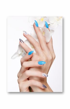 Beautiful summer blue manicure on female hand with flowers. Close-up. Picture taken in the studio