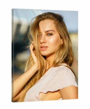 Closeup street portrait of sexy blonde girl with perfect makeup and hair, looking to the camera in sunny day