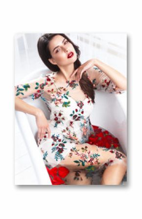 Beautiful girl in a summer dress in the bathroom with flowers. Beauty face. Photo taken in the studio