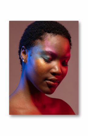 African american woman with short hair and colourful make up with eyes closed in blue and red light