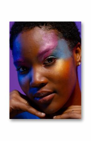 African american woman with short hair, colourful make up and hands under chin