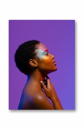 African american woman with short hair and colourful make up touching neck, with copy space