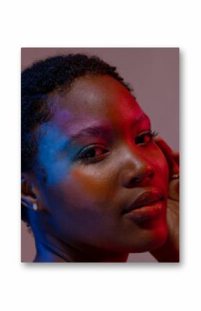 African american woman with short hair and colourful make up touching face