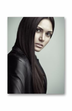 Closeup portrait of beautiful young brunette woman in a leather jacket. Long and straight brown hair. Natural makeup.