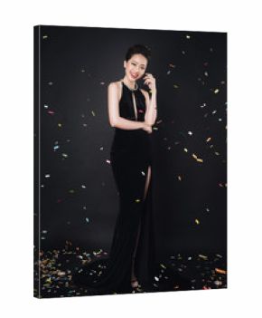 Asian woman with fashion makeup in luxury black dress while confetti falling on her.