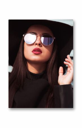 Fashion portrait of young beautiful model wears hat and sunglasses. Woman posing at the background of shutters in sunny day