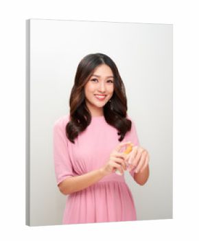 Smiling young asian woman showing skincare product.