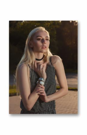 Gorgeous young model wearing chocker, bracelet and romper posing in the city at the evening
