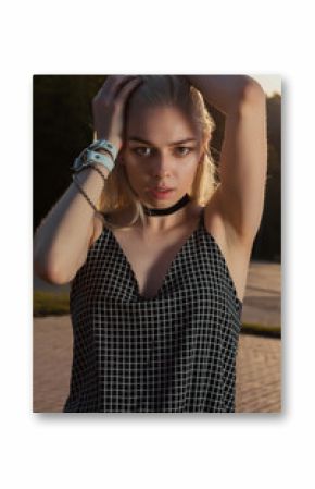 Closeup portrait of sexy blonde girl wearing chocker and bracelet, posing in the city at the evening