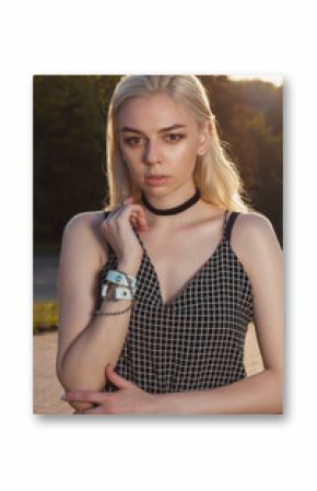Closeup portrait of beautiful tanned blonde woman in black romper posing at the city in rays of sun