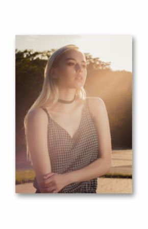 Closeup portrait of attractive blonde girl in black romper posing at the city in rays of sun