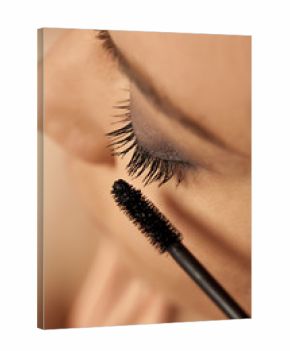 Closeup of young woman applying mascara