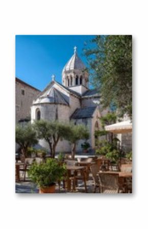 Historic Church Surrounded by Olive Trees and Outdoor Seating in Croatia on a Sunny Day