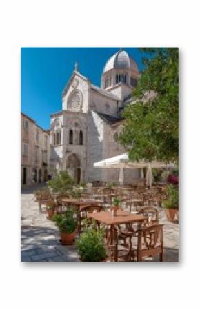 Historic Church Surrounded by Olive Trees and Outdoor Seating in Croatia on a Sunny Day.