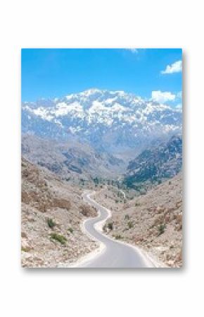 Winding Asphalt Road Through Steep Canyon Towards Snow Covered Mountain Peak