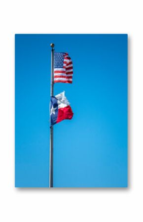 Torn American and Texas flags wave against a clear blue sky.