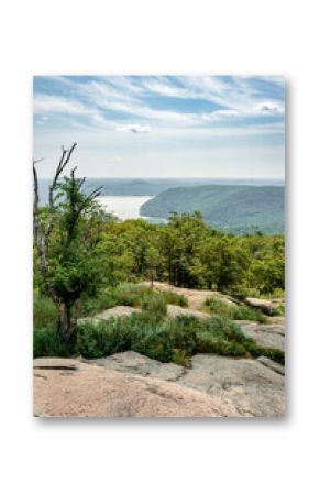 Stony Point, NY - US - Jul 3, 2025 From a rocky, elevated perch in Bear Mountain State Park, a scenic overlook reveals tree-covered mountains, the Hudson River, and a hazy sky dotted with clouds.