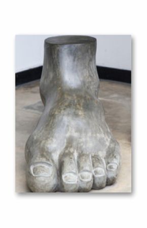 A large foot sculpture sits on a concrete floor