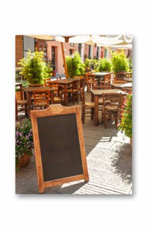 Empty outdoor cafe with blank chalkboard menu sign on a sunny street in Italy