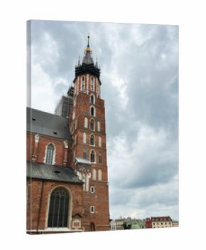 Historic Gothic church facade with tourists in a European city square in Krakow, Poland.
