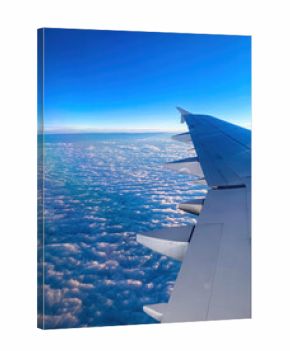 Passenger view of an airplane wing illuminated by sunrise above a dense blanket of clouds during high-altitude flight