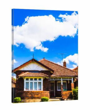 Charming single-story suburban house with a red roof and white picket fence under sunny skies. 