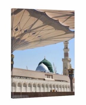 View of Al-Masjid an-Nabawi in Madinah Al Munawwarah, Saudi Arabia. The image features the iconic green dome and minarets. Intricate architectural details of the mosque are visible, including ornate