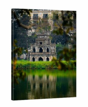 Ancient turtle tower in hoan kiem lake surrounded by lush greenery in Hanoi, Vietnam