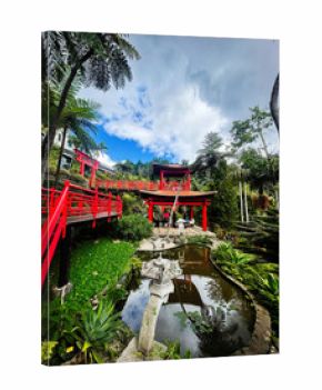 Bright red bridges and tranquil garden pavilion in Madeira Portugal with lush tropical scenery
