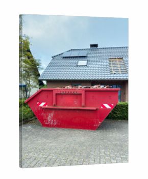 Bright red dumpster placed outside a brick house with missing roof tiles on a clear day highlights ongoing home renovations in a suburban neighborhood