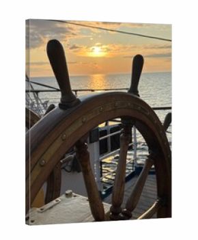 an antique ship's wheel at sunset at sea
