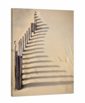 Wooden fence and shadows in the sand on the beach