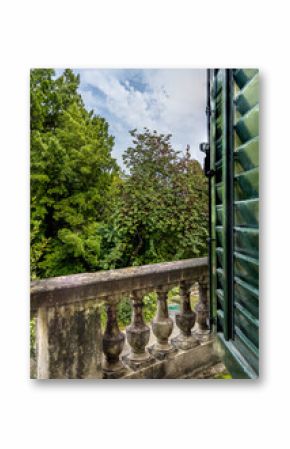 Balcony with a stone balustrade of an old historical palace leading to a park