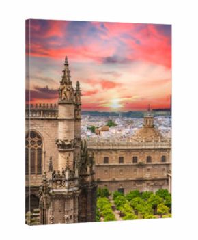 Seville Cathedral and orange tree courtyard at sunset with dramatic pink sky over the historic old town of Seville, Spain