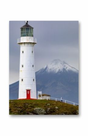 Cape Egmont Lighthouse stands tall on the coast of Pungarehu, Taranaki, New Zealand, guiding ships safely. The iconic landmark is set against the backdrop of Mount Taranaki.