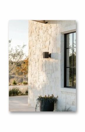 Natural stone wall complements minimalist exterior design with modern lighting and potted plant at sunset in a tranquil outdoor setting