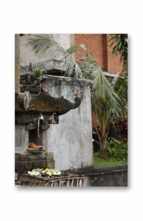 Different traditional balinese offerings on stone post