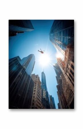Dynamic low-angle view of towe skyscrapers and modern glass buildings in a bustling city with a bright sun and a flying airplane high above the streets