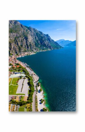 Aerial view of Limone sul Garda, a colorful lakeside town in Italy nestled between Lake Garda and steep mountains under a bright blue sky
